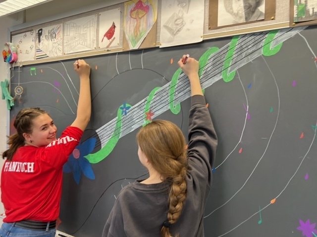 two students creating a chalk mural